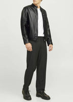 Man wearing a black leather jacket, white shirt, and black pants on a white background