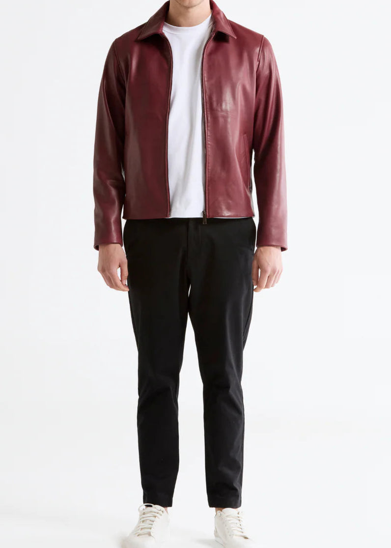 Man wearing a red leather jacket, white shirt, black pants, and white sneakers on a white background