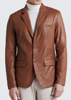 Man wearing a brown leather blazer over a white turtleneck on a light gray background